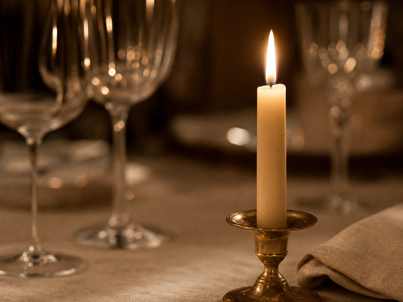 Close-up of candlelight and detail on a set dining table