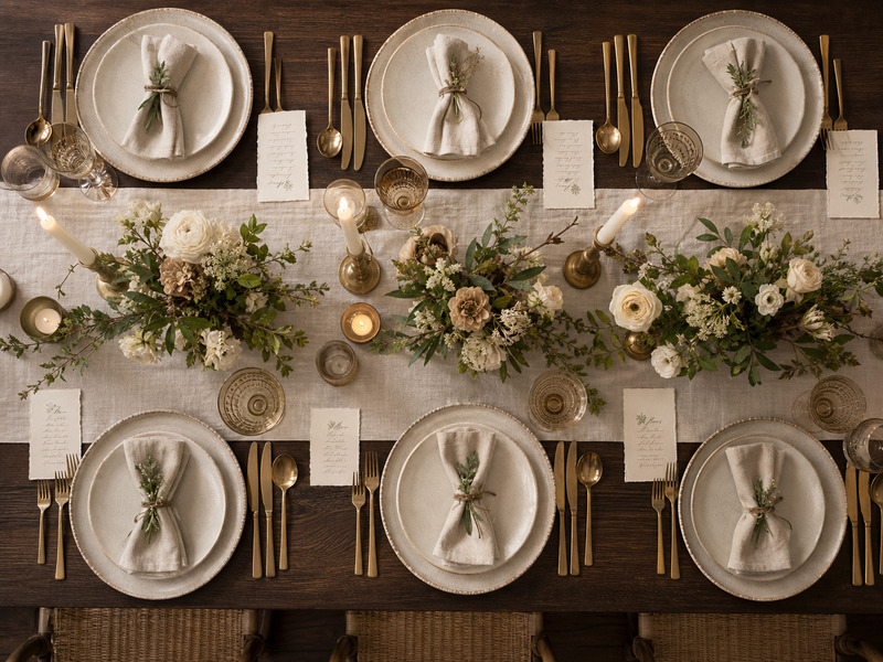 Overhead tablescape with layered linens, taper candles, and gold flatware